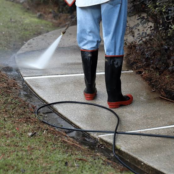 Professional pressure washing a residential concrete sidewalk